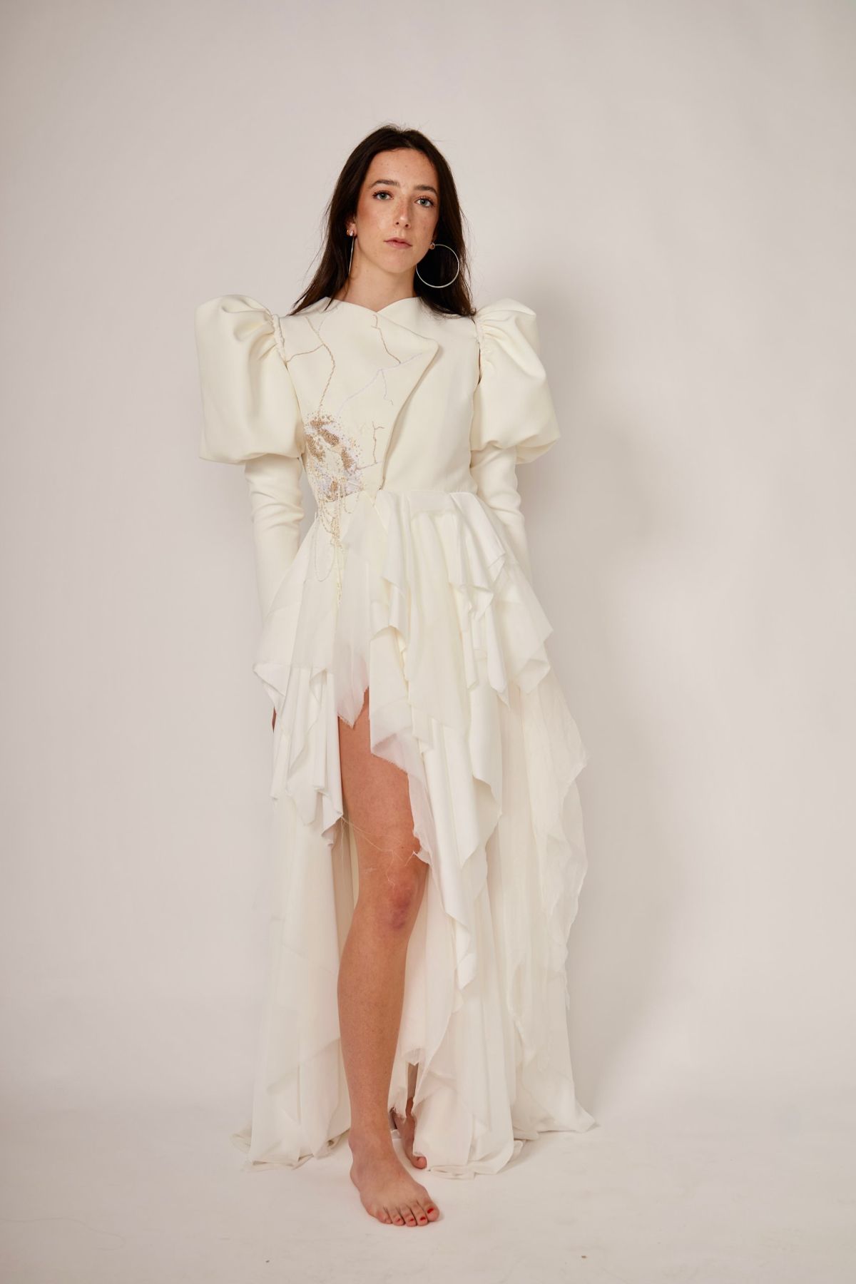 Vestido blanco de mangas abullonadas, cuerpo bordado y falda de volantes asimétricos